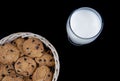 Fresh Milk and Chocolate chip cookies in a bamboo basket isolated on black background Royalty Free Stock Photo