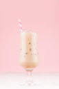 Fresh milk cocktail with coffee, ice cubes, and straw on light pastel pink wall and white wood board, vertical. Royalty Free Stock Photo