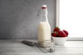 Fresh milk,cream bottle on window sill with strawberries Royalty Free Stock Photo