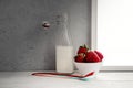 Fresh milk,cream bottle on window sill with strawberries in bowl Royalty Free Stock Photo