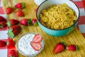 Fresh milk in glass bottle, cereals in green blue ceramic bowl, tasty yogurt in small glass bowl with a lot of strawberries around Royalty Free Stock Photo