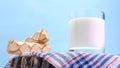 Fresh milk in a glass with pastries on a wooden board on a blue background. Dairy product close-up. White yogurt in a glass