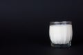 Fresh milk in a glass transparent glass, on a dark background.