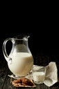 fresh milk in jug and glass, chocolate cookies and sackcloth on black background Royalty Free Stock Photo