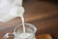 Fresh milk natural in bottle and  Pouring milk into glass jug on wooden background Royalty Free Stock Photo