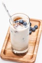 Milk with ice coffee cubes and fresh blueberries on wooden rectangular plate