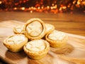 Fresh mince pies on a wooden board. Traditional Christmas pastry product. Warm glitter bokeh background