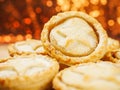 Fresh mince pies on a wooden board. Traditional Christmas pastry product. Warm glitter bokeh background