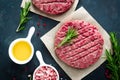 Fresh minced beef meat burgers with spices on dark background. Raw ground beef meat