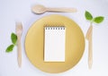 fresh mint and notepad for menu on yellow plate with wooden cutlery, copy space Royalty Free Stock Photo