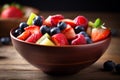 fresh mixed berries and fruit salad in bowl on top of wooden table Royalty Free Stock Photo