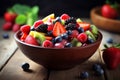 fresh mixed berries and fruit salad in bowl on top of wooden table Royalty Free Stock Photo