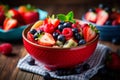 fresh mixed berries and fruit salad in bowl on top of wooden table Royalty Free Stock Photo