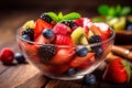 fresh mixed berries and fruit salad in bowl on top of wooden table Royalty Free Stock Photo