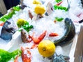 Fresh mixed raw fish and red prawns in ice with lemon and lettuce leaves Royalty Free Stock Photo