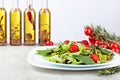 Fresh mixed salad with cherry tomatoes on white plate. Bottles of olive oil with spices and herbs Royalty Free Stock Photo