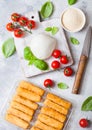 Fresh Mozzarella cheese on vintage chopping board with tomatoes and basil leaf and tray with cheese sticks on stone kitchen table Royalty Free Stock Photo