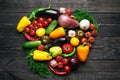 Fresh multi-colored vegetables rich in vitamins on a dark wooden background are located in the middle in the shape of a heart.