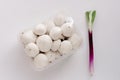 Fresh mushrooms white champignons in plastic packaging and green onions shallots or scallions on white background. Royalty Free Stock Photo