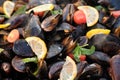 Fresh mussels at grill pan. Mussels in shells cooking with herbs, lemon and tomato on grill outdoors Royalty Free Stock Photo