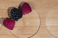 Fresh natural berries of raspberry and blueberry lie on a textured wooden board with circle cuts, top view