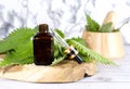 Fresh nettle in wooden mortar. Preparation of elixirs from medicinal herbs by herbalists. The essential oil in the pharmacy bottle