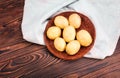 Fresh and new potatoes in a dark brown basket on a light grey box and on a wooden background.Uncooked, whole and ripe potatoes. Royalty Free Stock Photo