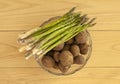 Fresh new potatoes with peel on and green asparagus in a glass bowl. Top view image on wooden background Royalty Free Stock Photo