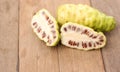 Fresh noni slice and noni fruit on wooden background. Royalty Free Stock Photo