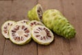 Fresh noni slice and noni fruit on wooden background. Royalty Free Stock Photo