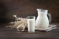 Fresh oat milk in glass and pitcher on dark wooden table. Rustic style Royalty Free Stock Photo