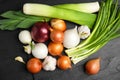 Fresh onion bulbs, leeks and garlic on black table, flat lay Royalty Free Stock Photo