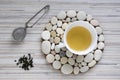 Fresh oolong tea in white pot on stones circle tray on light striped table