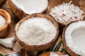 Fresh opened coconuts along with coconut slices, flakes and coconut leaves on a wooden table