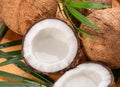 Fresh opened coconuts along with whole coconuts and coconut leaves on a wooden table Royalty Free Stock Photo