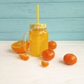 Fresh orange fresh clear glass with straw from white and blue wooden, mandarins