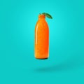 Fresh orange juice in a bottle on a blue background. Natural orange bottle with a leaf. Creative healthy product. Summer concept.