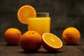 Fresh orange juice and fruits whole and sliced on a wooden table - natural and healthy food and drink. One glass of cocktail with Royalty Free Stock Photo