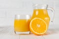 Fresh orange juice in glass and jug, half of citrus on white wooden background. Healthy eating, diet theme. Juicy fruit. Closeup p Royalty Free Stock Photo