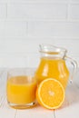 Fresh orange juice in glass and jug, half of citrus on white wooden background. Healthy eating, diet theme. Juicy fruit. Closeup p Royalty Free Stock Photo