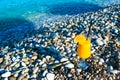 Fresh orange juice in a glass with a straw and an orange slice on a pebble beach against the backdrop of a clear calm blue sea Royalty Free Stock Photo