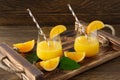 Fresh orange juice in glasses with cut oranges on wooden tray. Rustic still life with citrus fruits Royalty Free Stock Photo