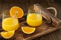 Fresh orange juice in glasses with cut oranges on wooden tray. Rustic still life with citrus fruits Royalty Free Stock Photo