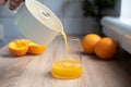 Fresh orange juice pouring from a juicer into a glass with squeezed oranges Royalty Free Stock Photo