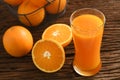 Fresh orange juice in tall glass with basket of oranges on wood Royalty Free Stock Photo