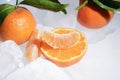 Fresh orange mandarin fruit with green leaves are frozen on cold blue ice. Royalty Free Stock Photo