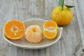 Fresh orange peeled and cut half on plate on wooden background Royalty Free Stock Photo