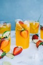 Fresh orange strawberry mojito in different glasses with ice cubes and slices of lime on the table. Summer refreshing drink Royalty Free Stock Photo