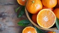 Fresh oranges in a basket with a sliced orange on a wooden table