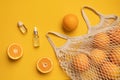 Fresh oranges in a eco bag. Cutted citrus fruit for healthly food. A bottle of essential oils.